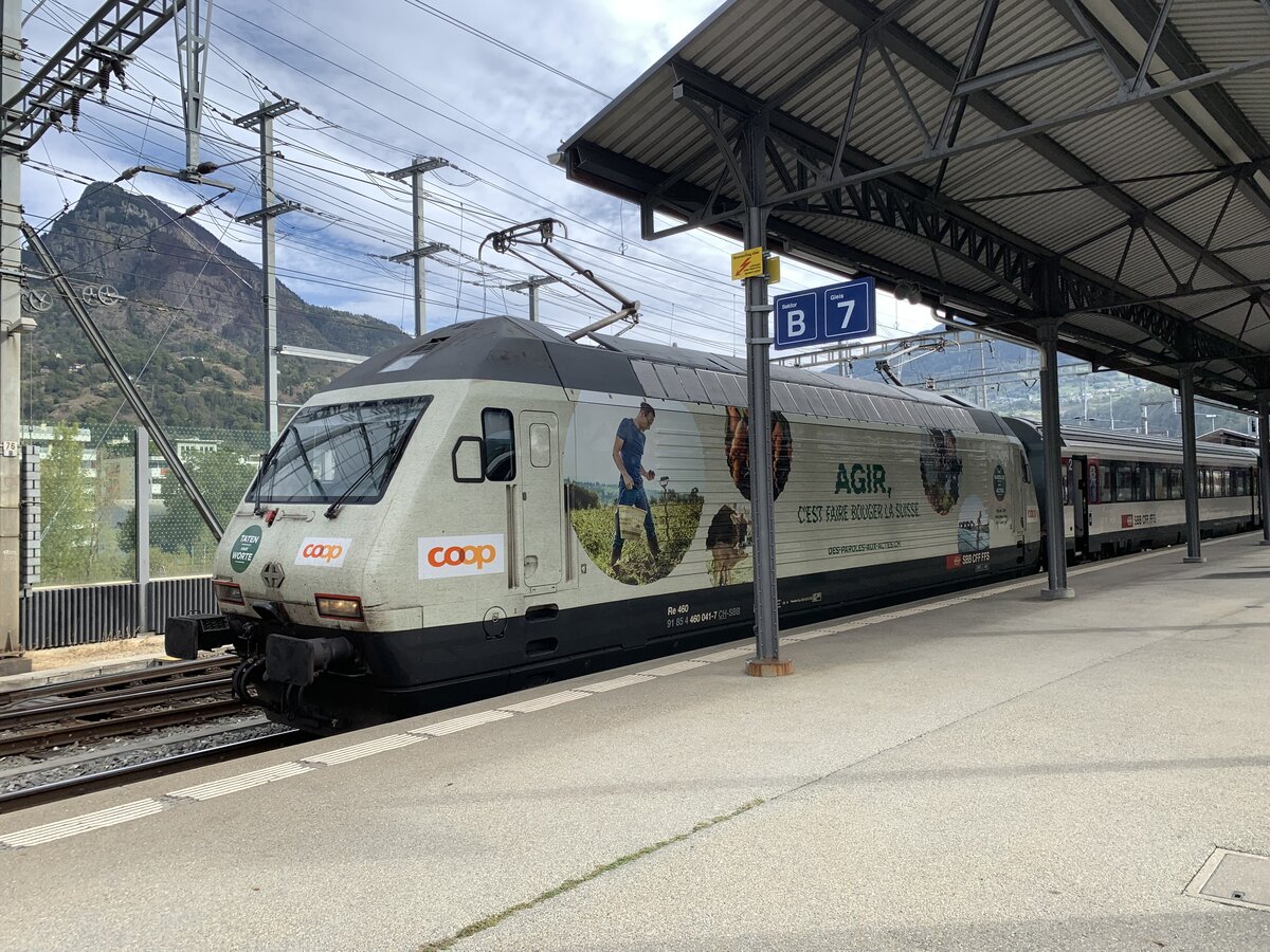 Die Re 460 041 mit Vollwerbung Coop Tatendrang am 16.10.23 im Bahnhof Brig.